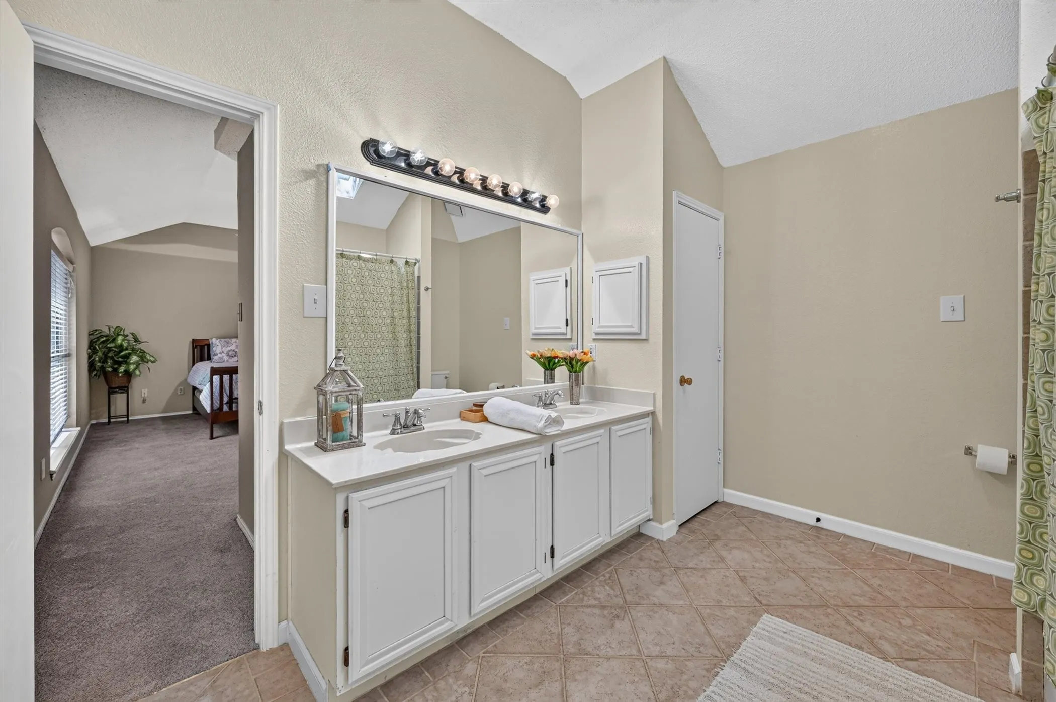 Bathroom featuring a double vanity with white cabinetry, dual undermount sinks, and a single-piece countertop