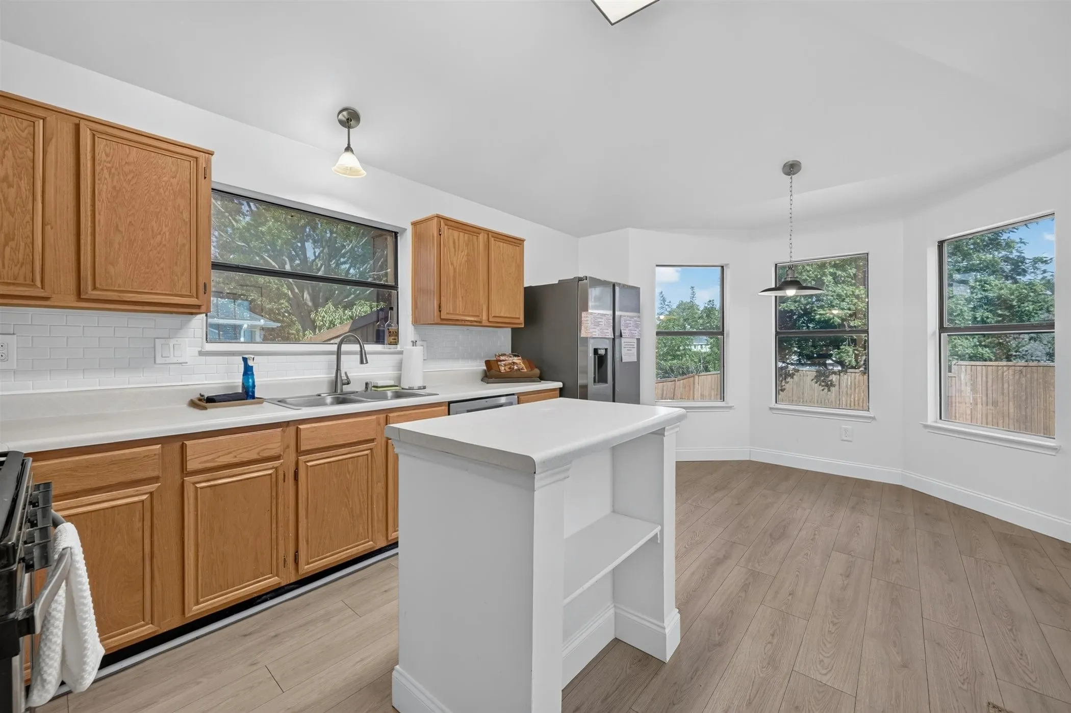 Kitchen featuring light wood cabinetry, white subway tile backsplash, and a contemporary pendant light fixture
