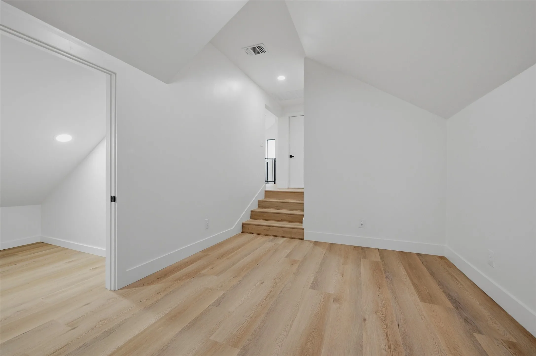 Open-concept space featuring wood-finish flooring, white walls, and a recessed lighting fixture