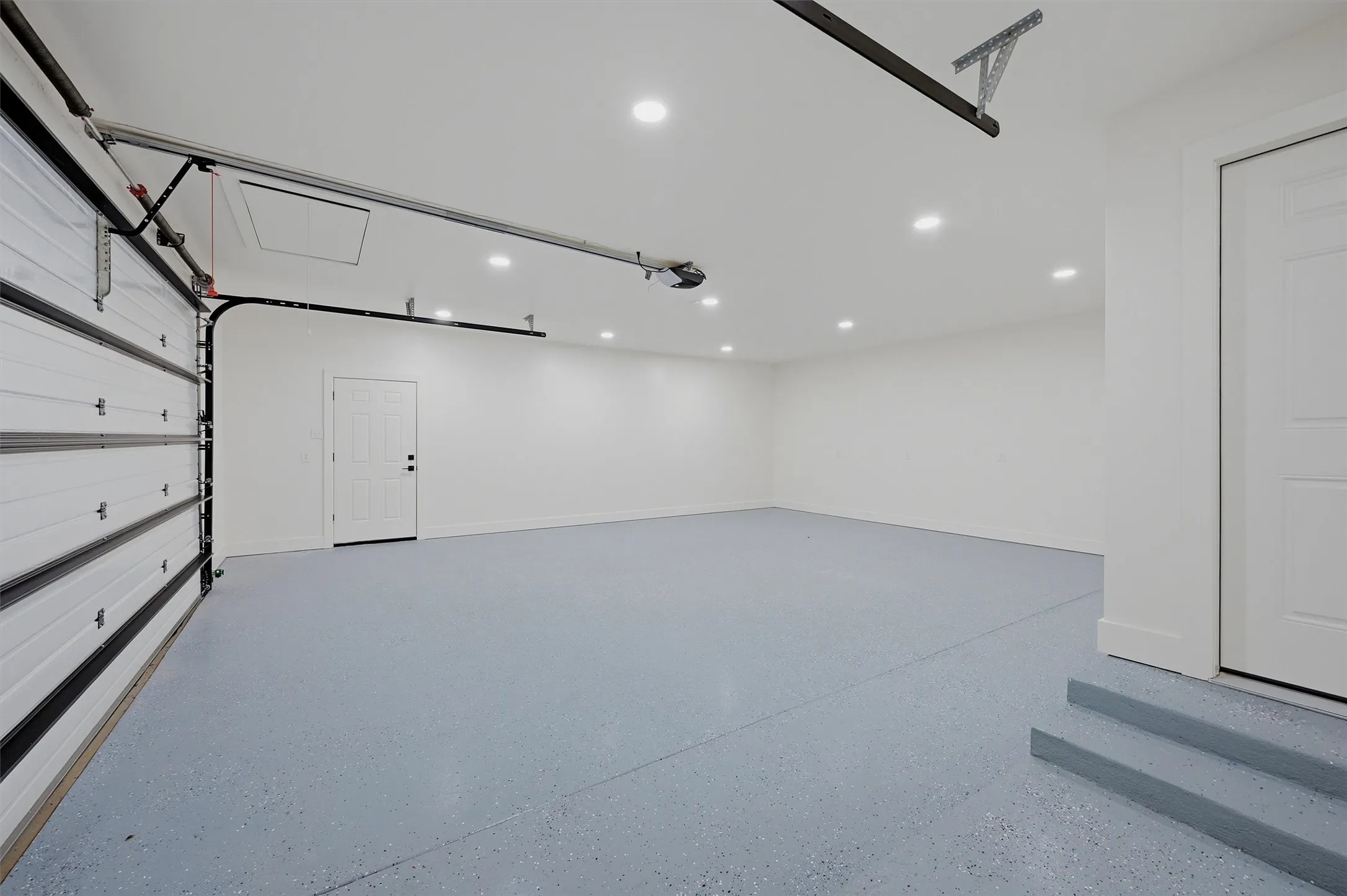 Spacious garage featuring an epoxy-coated floor, recessed lighting, and bright white walls