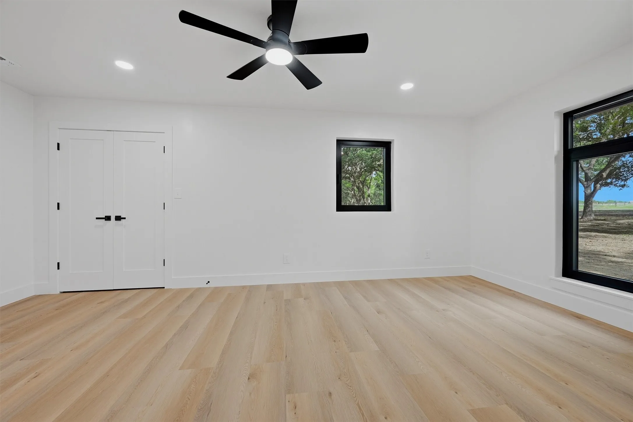 Light wood-finish flooring complements the crisp white walls and recessed lighting