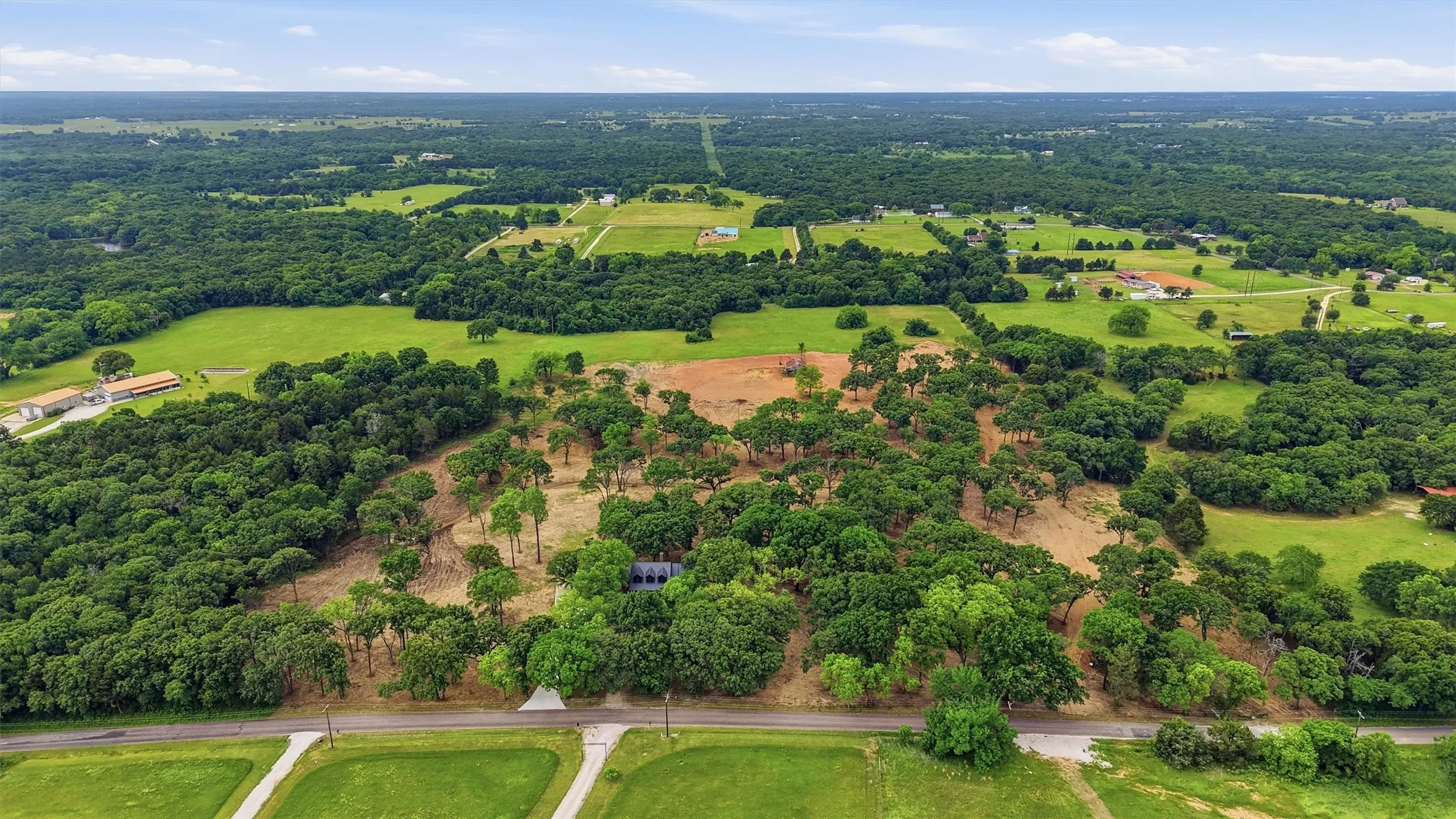 Expansive rural property featuring a mix of cleared land and mature trees