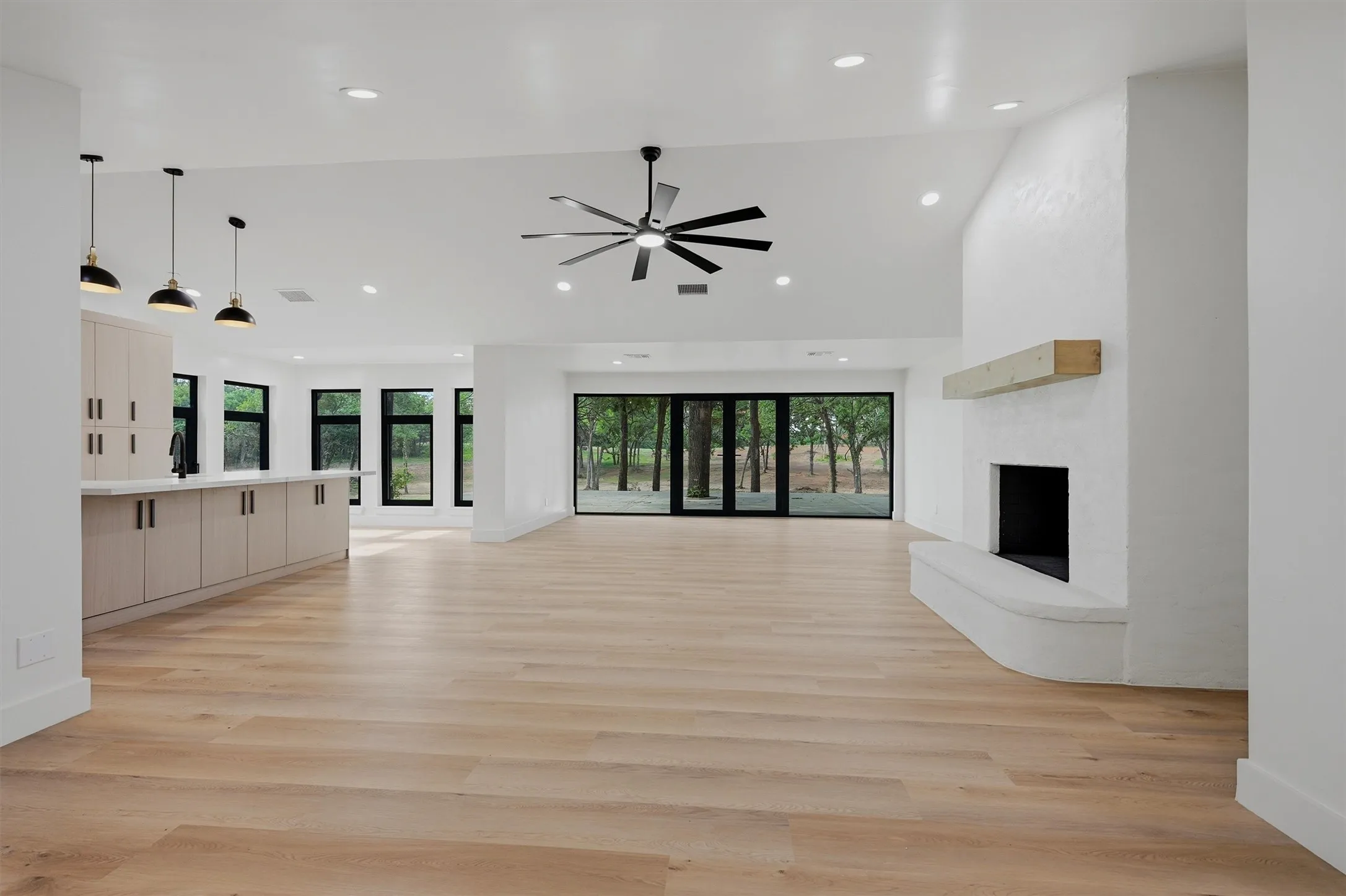 Vaulted ceilings with recessed lighting, an expansive fireplace, and wood-finish flooring define this open-concept space