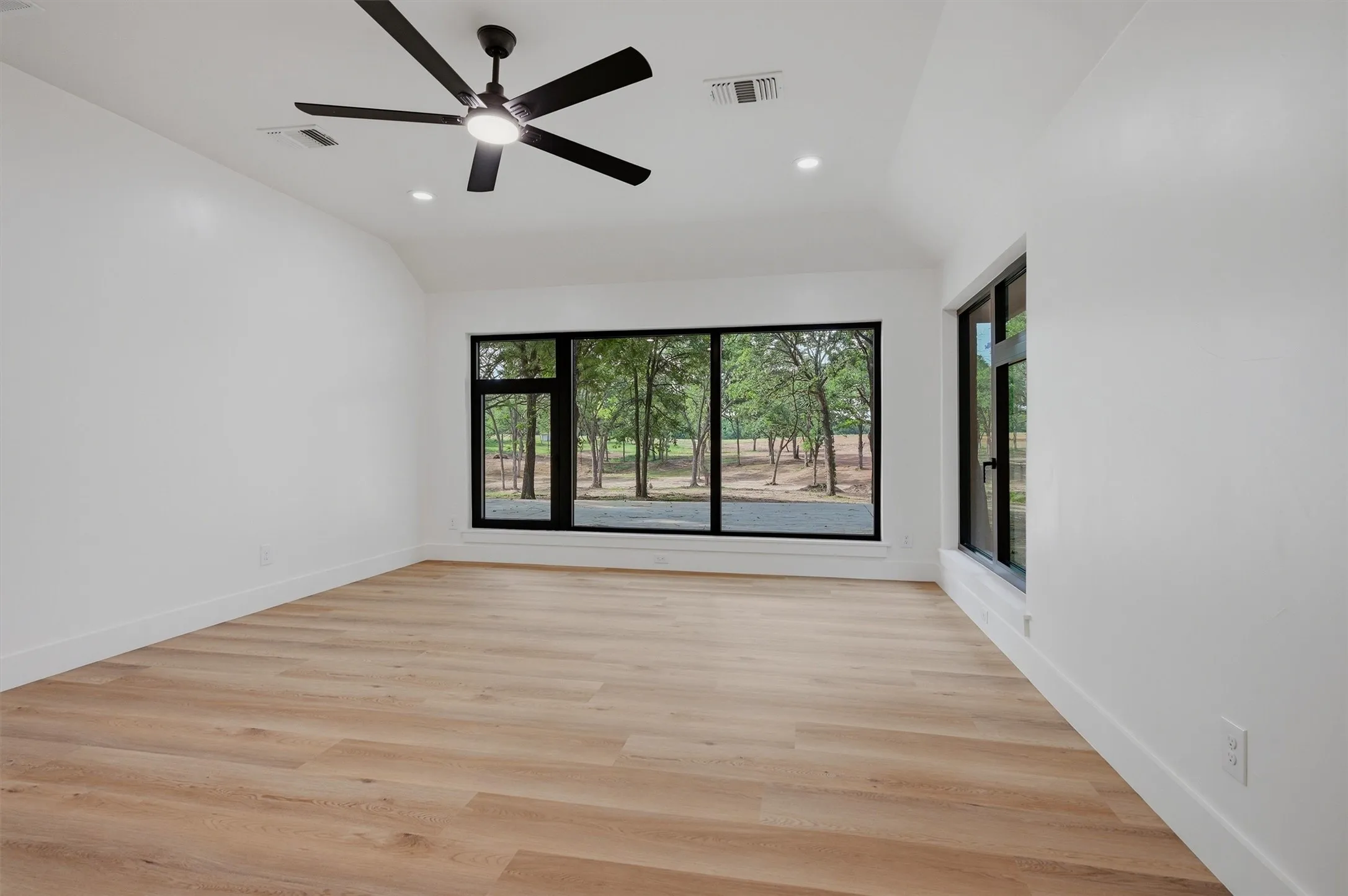 Bright interior space featuring wood-finish flooring, white walls, and a contemporary black ceiling fan