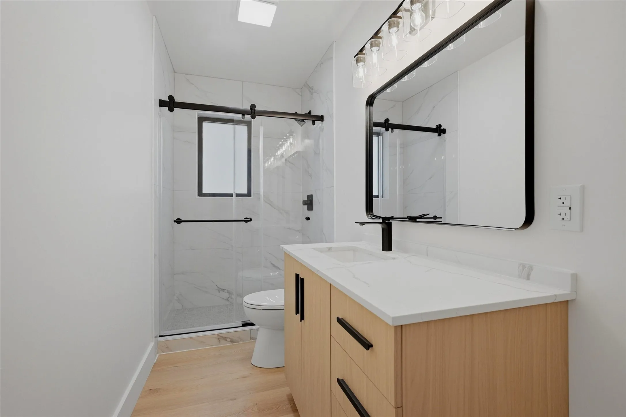 Modern bathroom featuring a wood-finish vanity with a white countertop and integrated sink