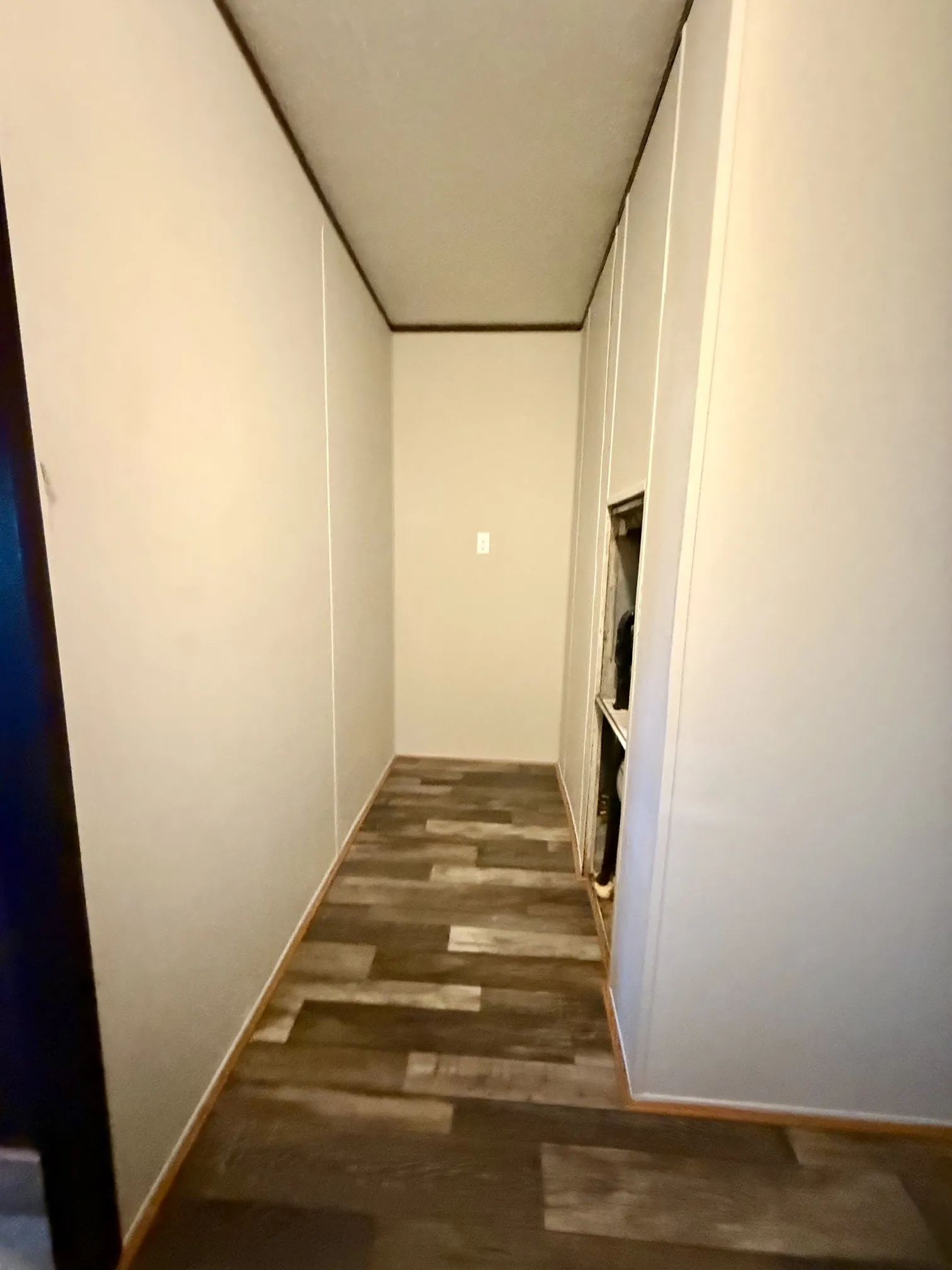 Corridor featuring wood-finish flooring, light-colored walls, and dark trim