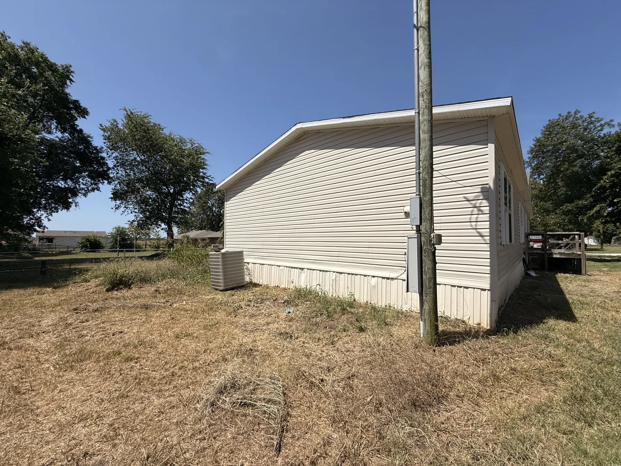 Side exterior with horizontal siding, a utility pole with electrical box, and an HVAC unit