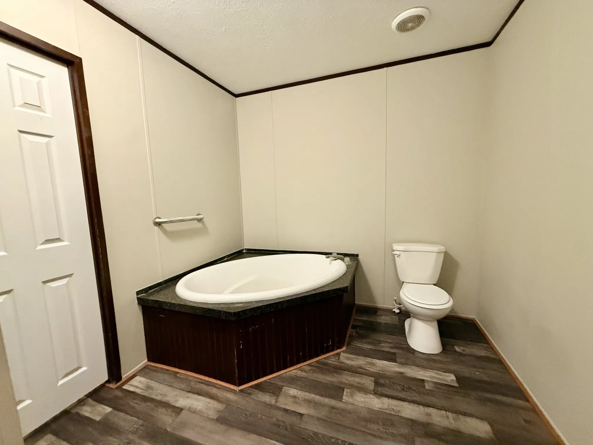 Corner garden tub with dark-toned surround and contrasting light flooring