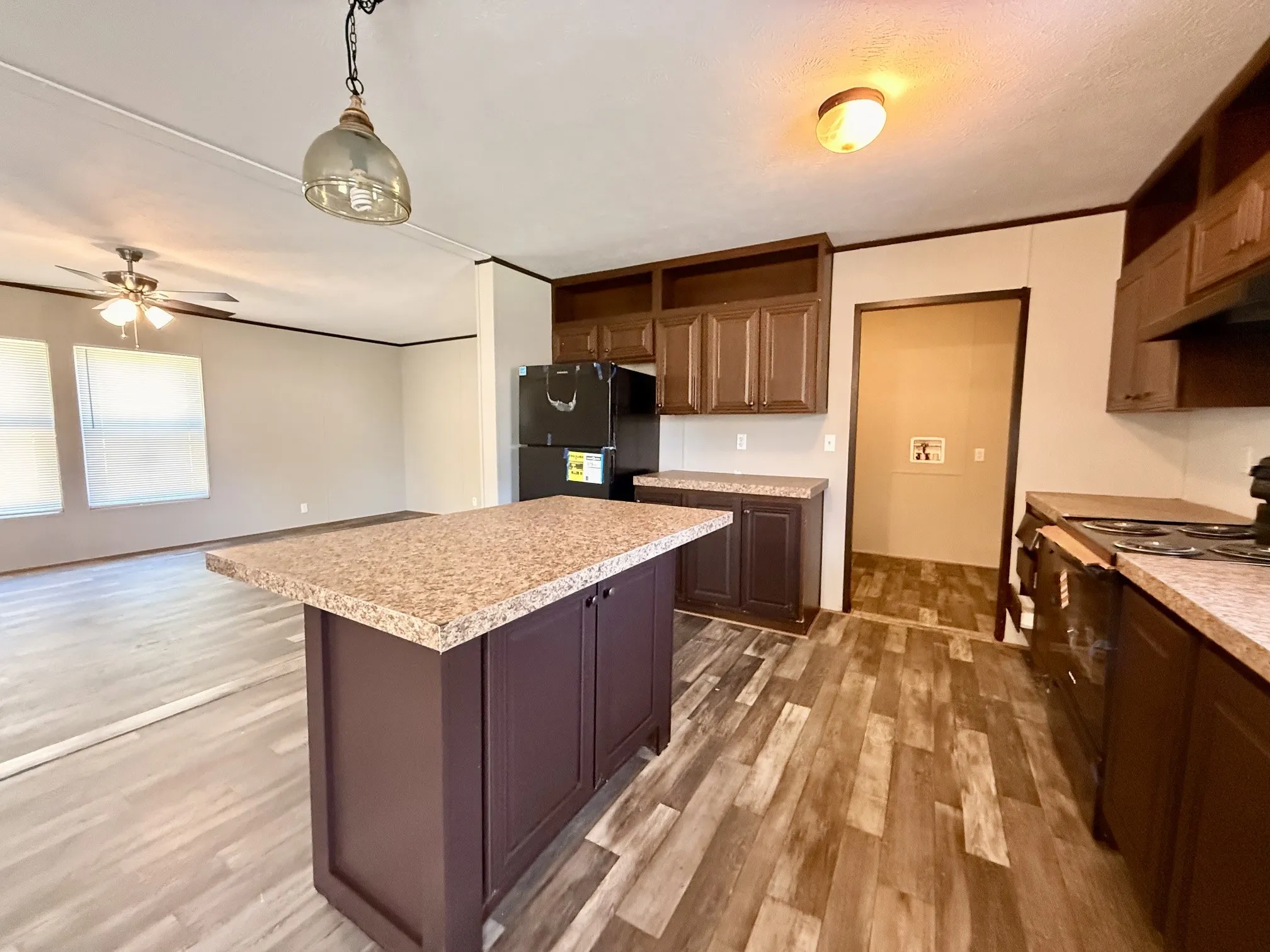 Kitchen featuring a central island with a speckled countertop, brown cabinetry, and wood-finish flooring