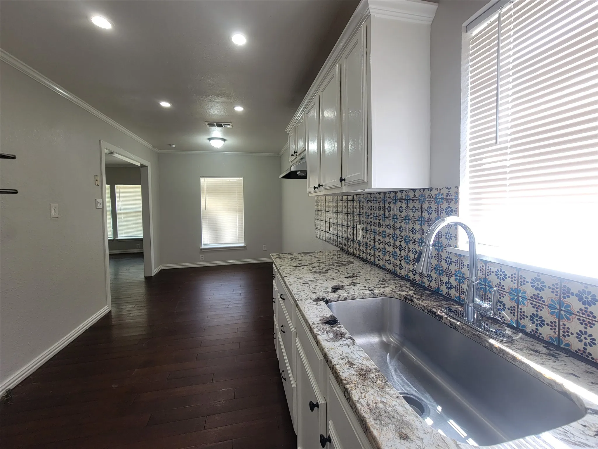 Kitchen featuring a stainless steel undermount sink, a pull-down faucet, granite countertops, and patterned tile backsplash