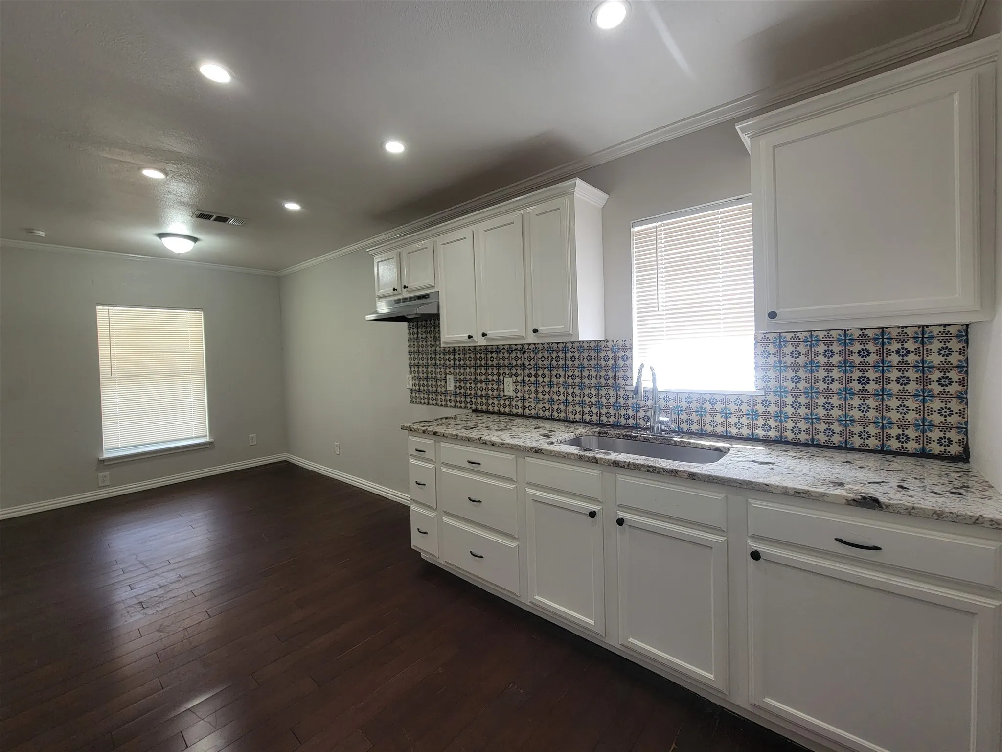 Kitchen area featuring white cabinetry, a patterned tile backsplash, and light-toned countertops