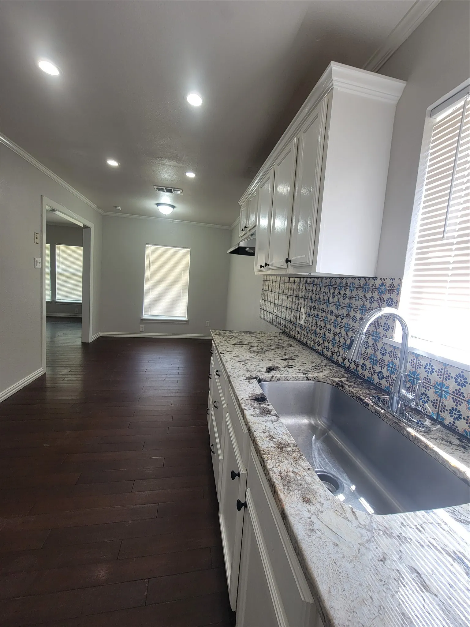 Modern kitchen featuring white cabinetry, a patterned tile backsplash, and a stainless steel undermount sink