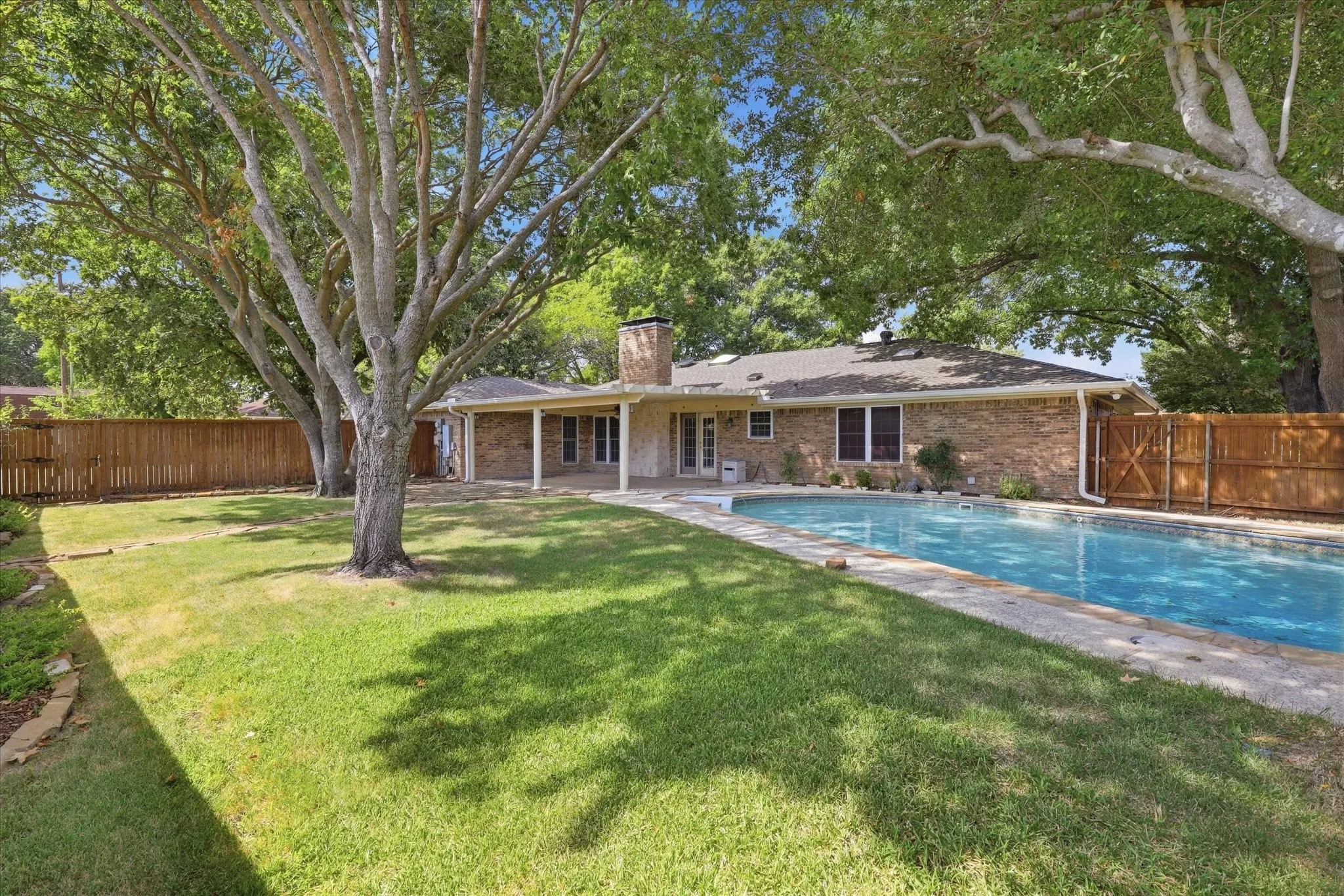 Large, fenced backyard with a covered patio and pool.