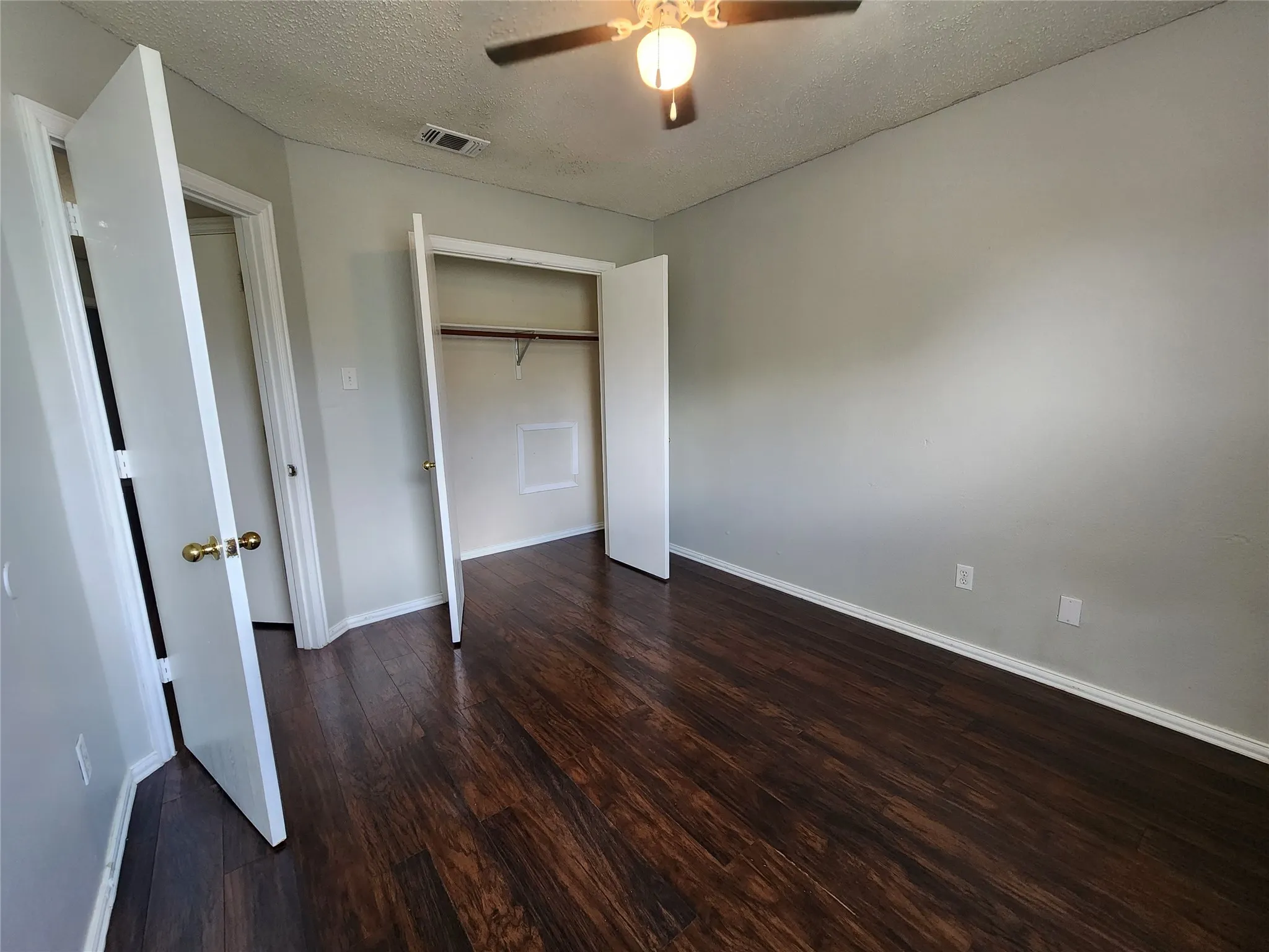 Room featuring dark wood-finish flooring, light grey walls, and white trim