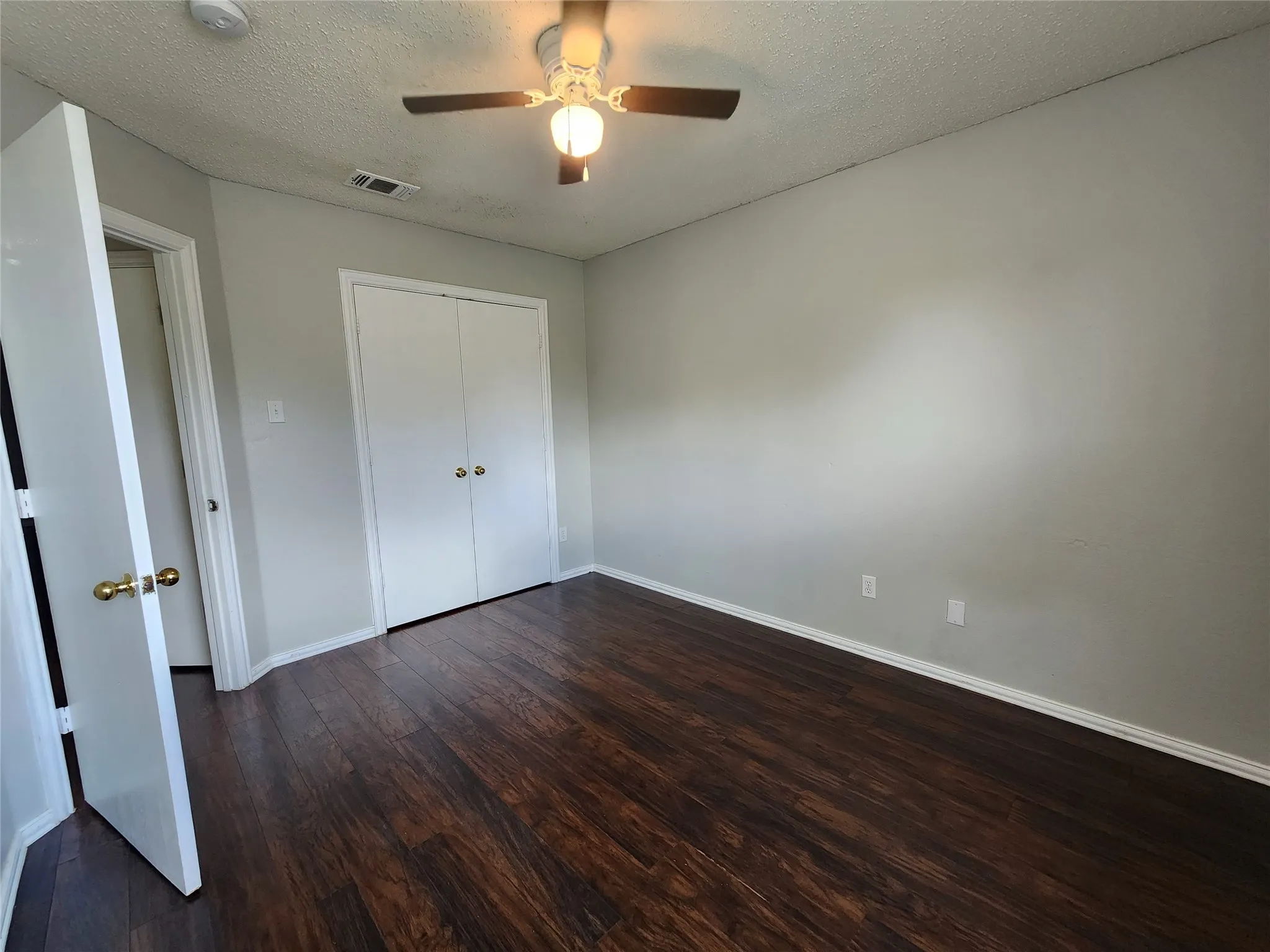 Spacious interior with dark wood-finish flooring, light gray walls, and white trim