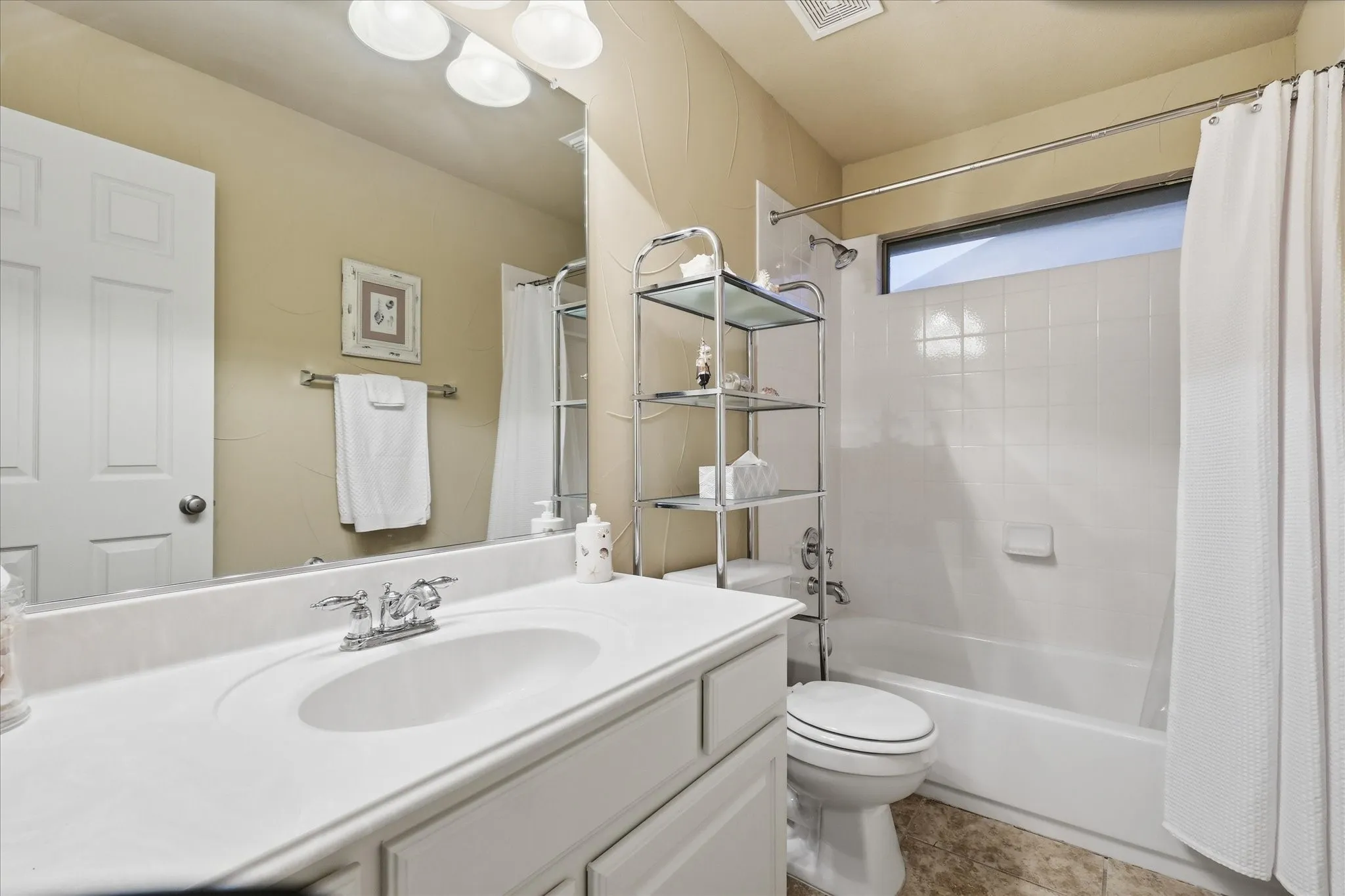 Bathroom with a white vanity, integrated sink, and chrome faucet