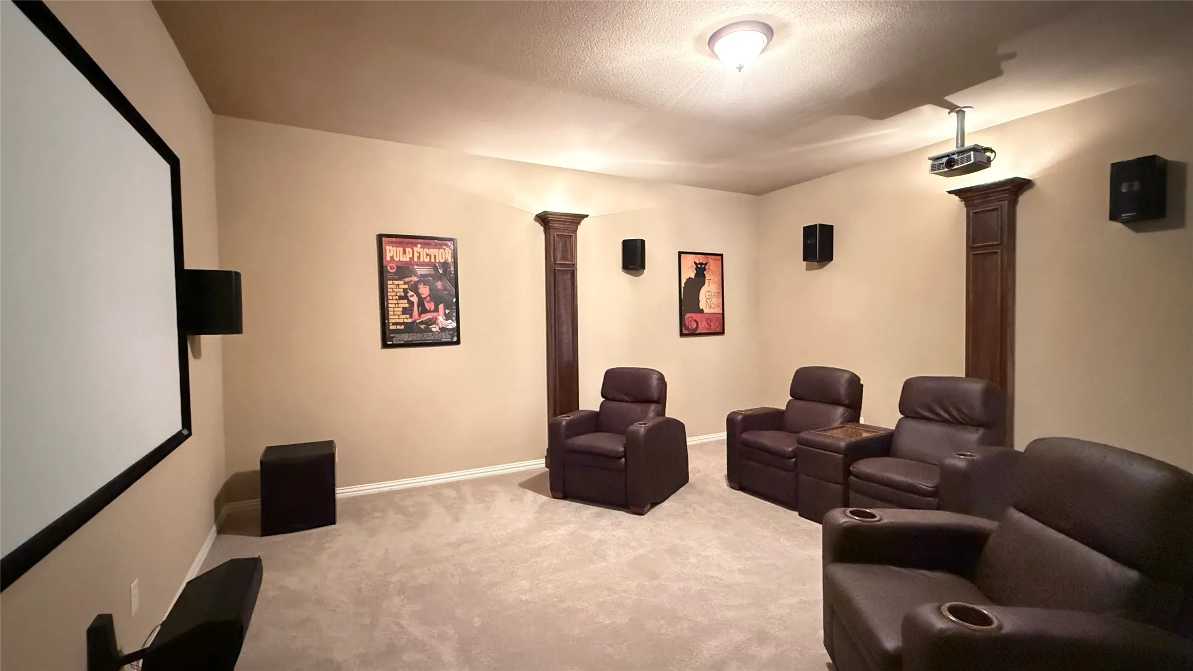 Dedicated media room featuring a large projection screen, mounted projector, and integrated wall speakers