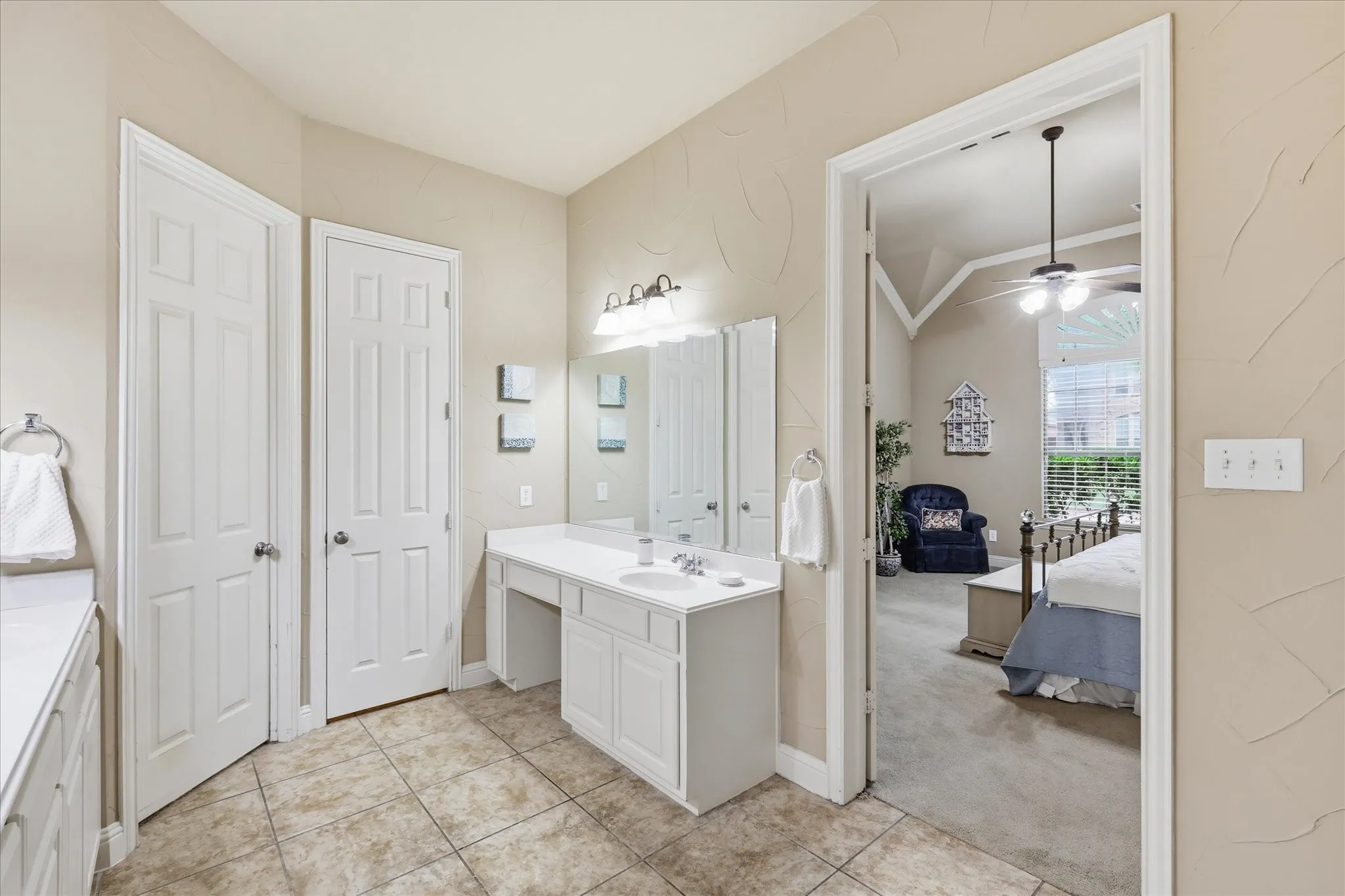Bathroom vanity with dual sinks, white cabinetry, and a dedicated vanity area
