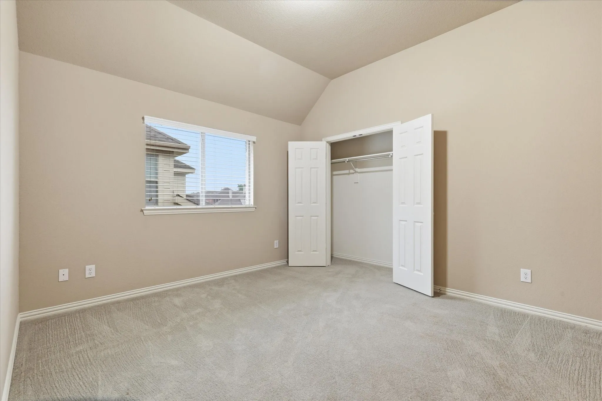 Carpeted room featuring a double-door closet, a single window with blinds, and neutral-toned walls