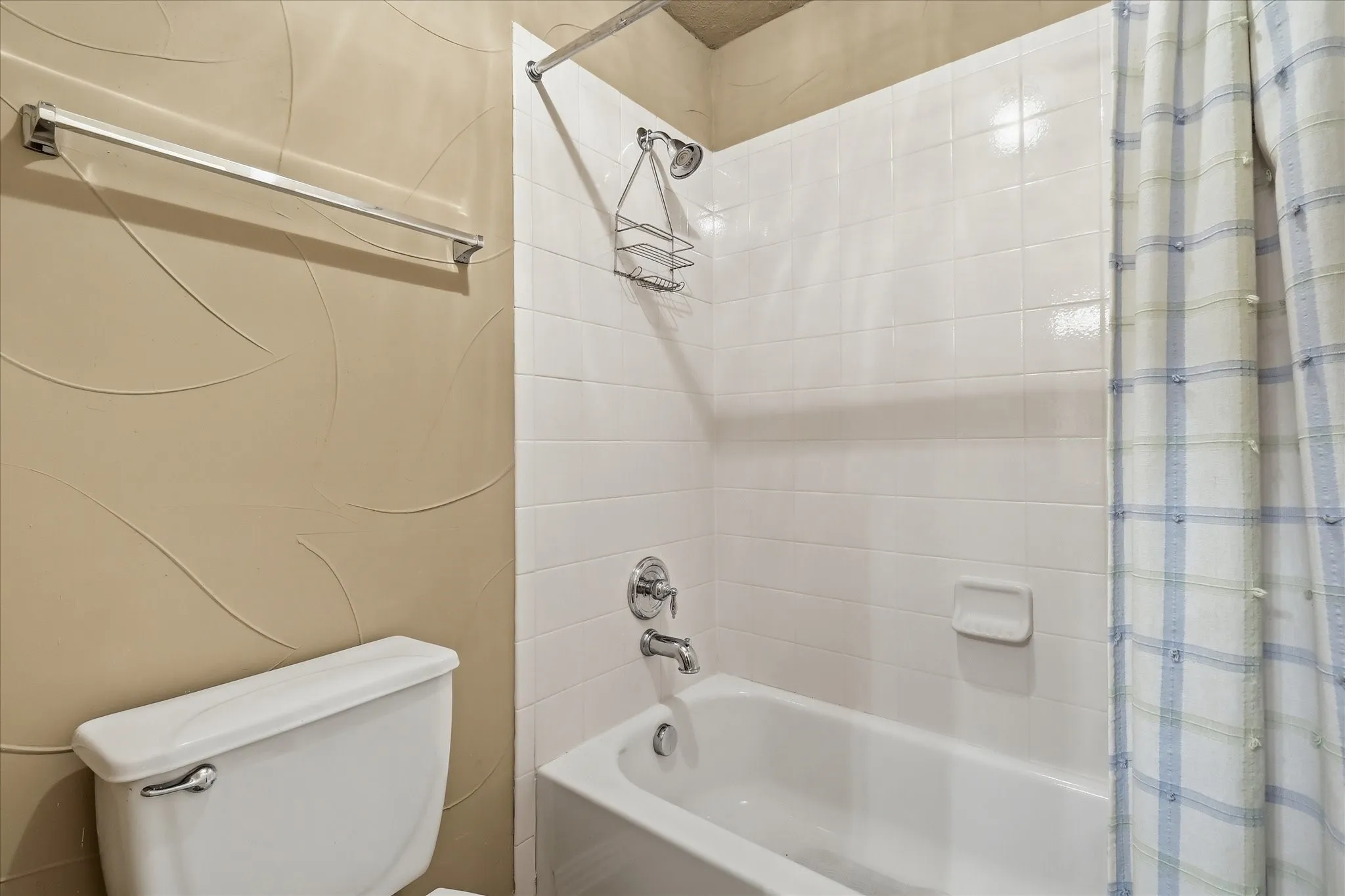 White tiled tub and shower combination with chrome fixtures