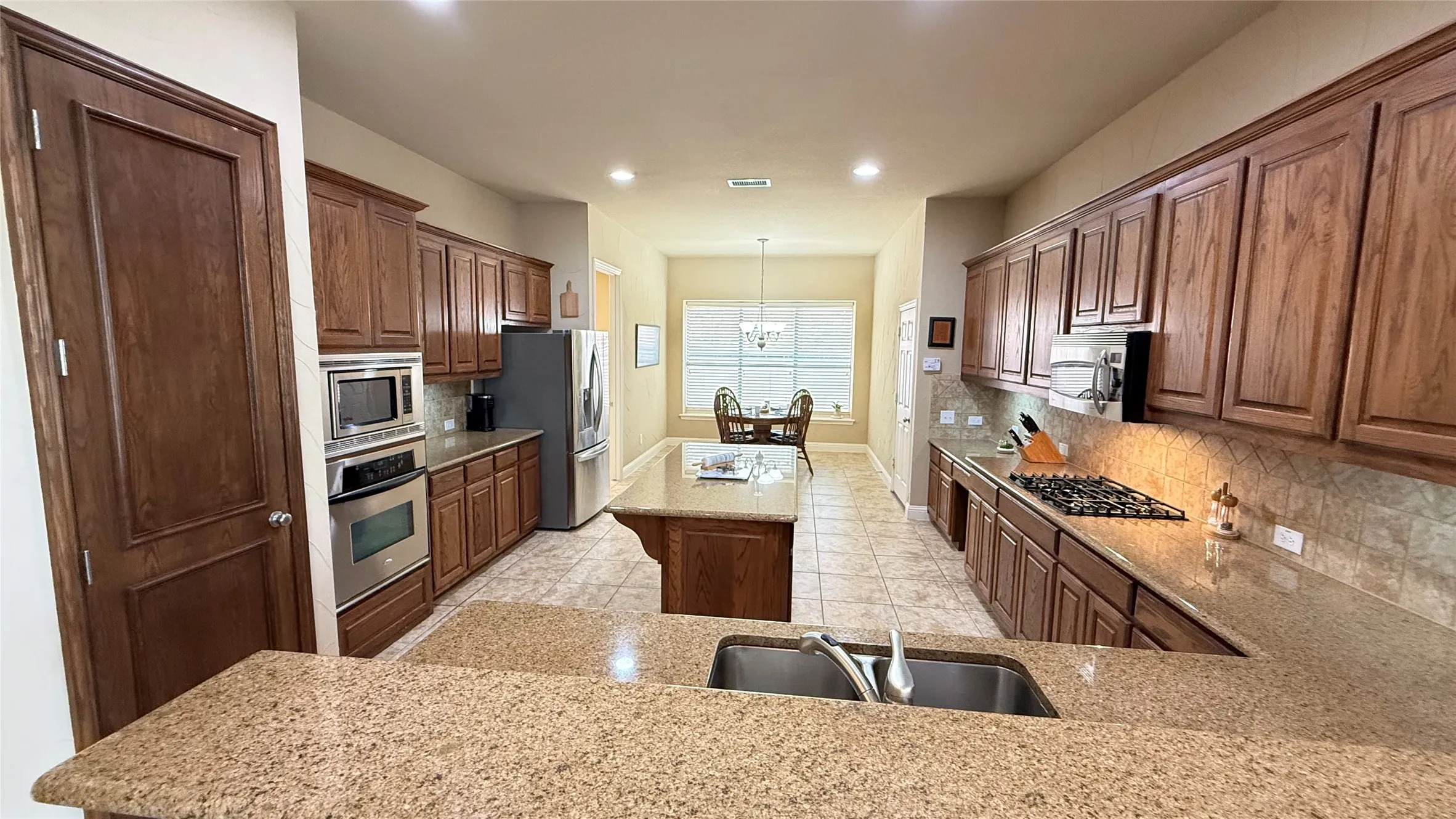 Spacious kitchen featuring extensive cabinetry, stone-finish countertops, and stainless steel built-in appliances