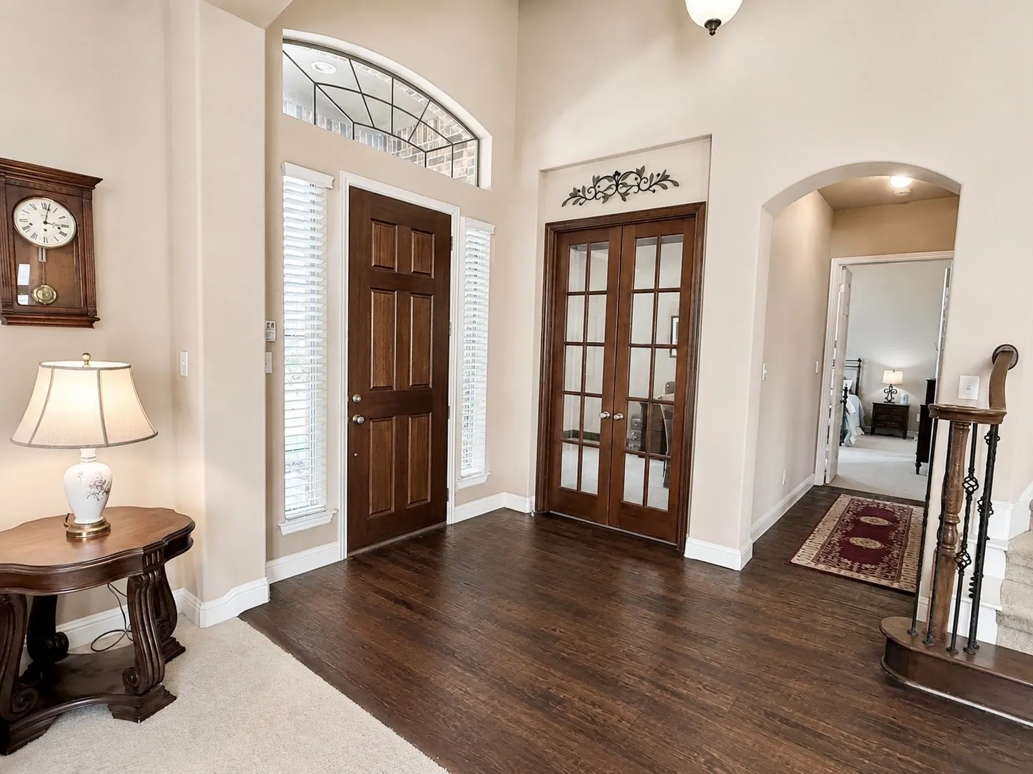 Entryway featuring wood-finish flooring, a solid wood front door with sidelights, and an arched transom window