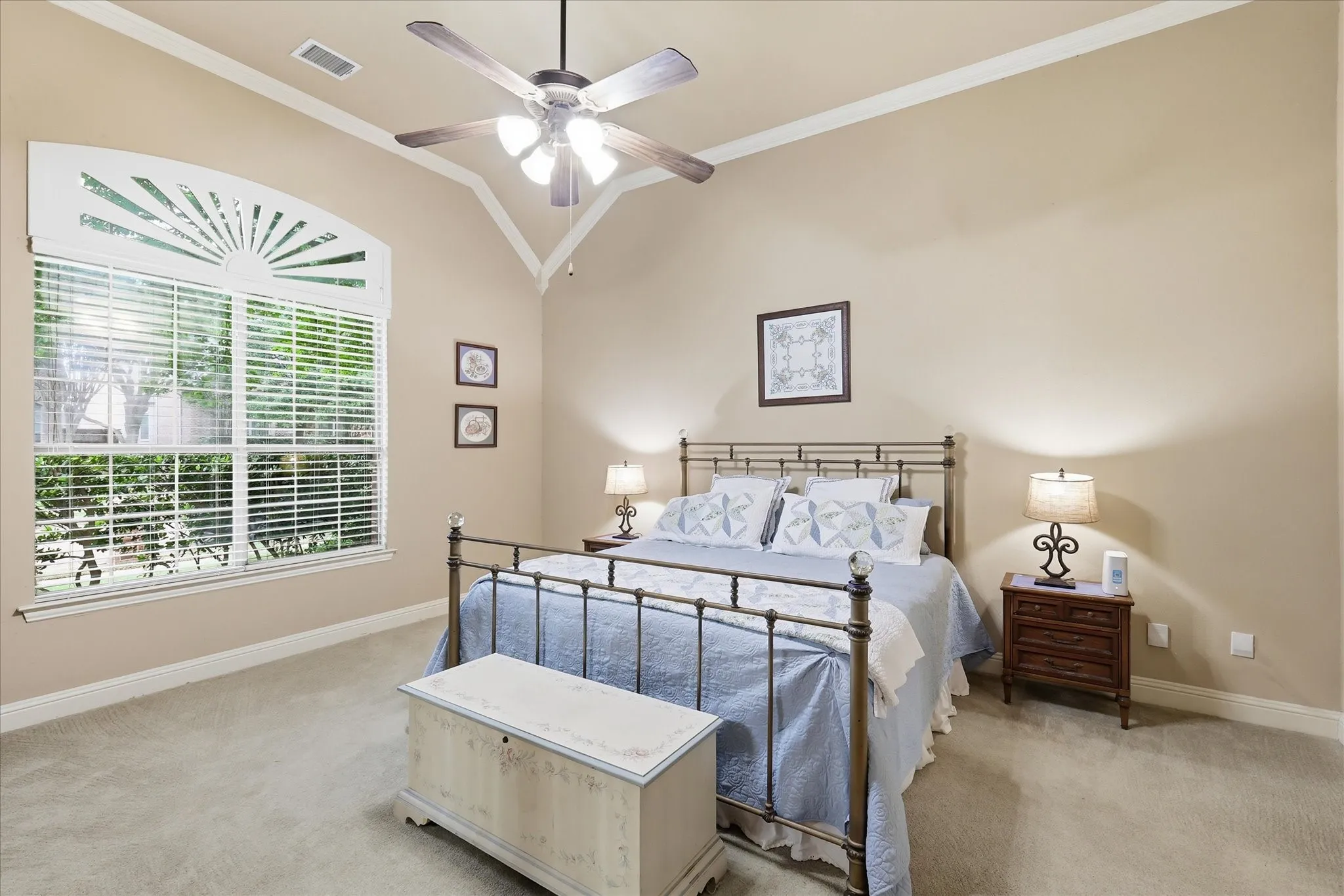 Vaulted ceiling room featuring a decorative arched window with blinds, light-toned carpeting, and a ceiling fan with integrated lighting