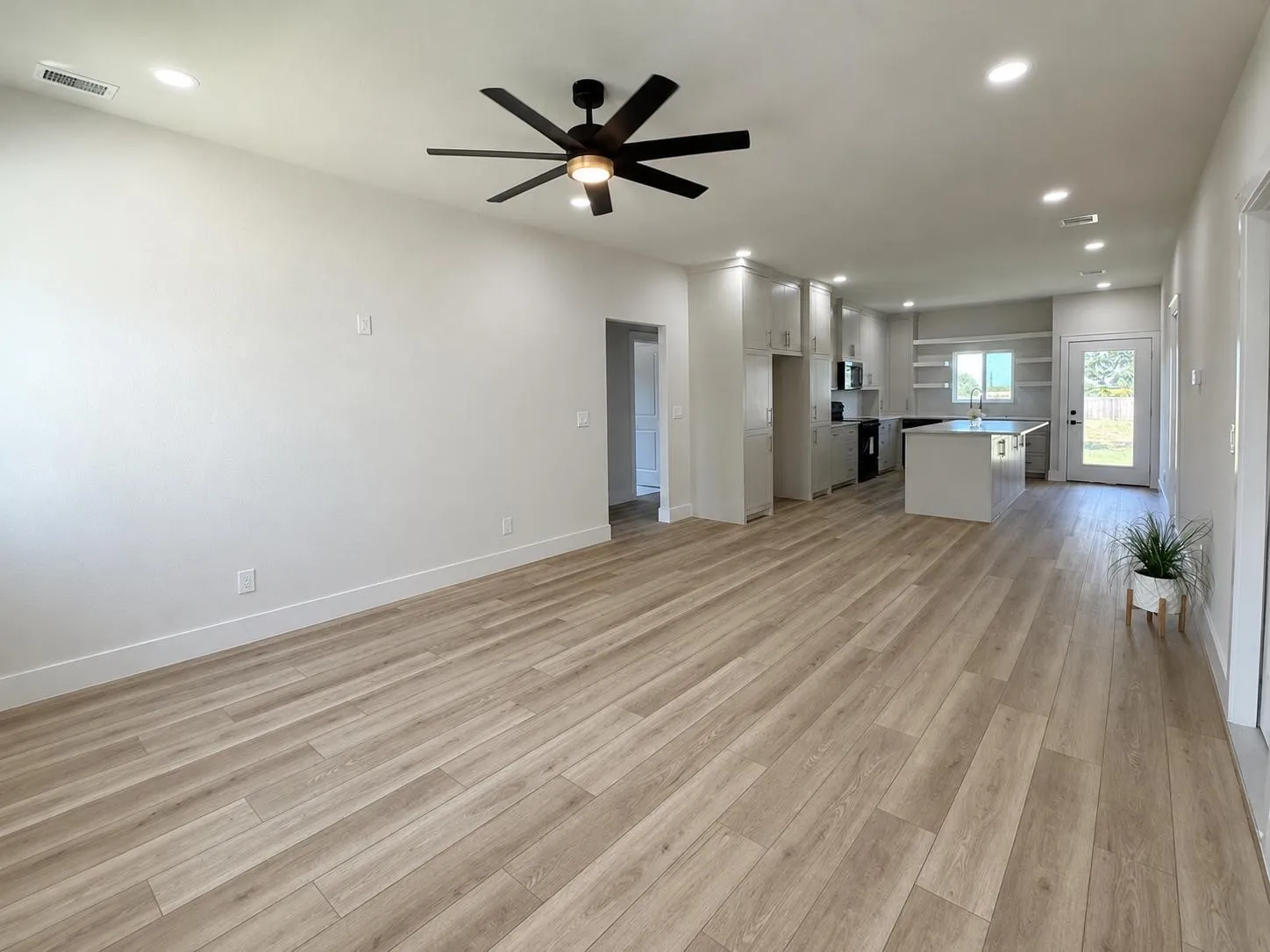 Spacious open-concept living area featuring wood-finish flooring, recessed lighting, and a modern ceiling fan