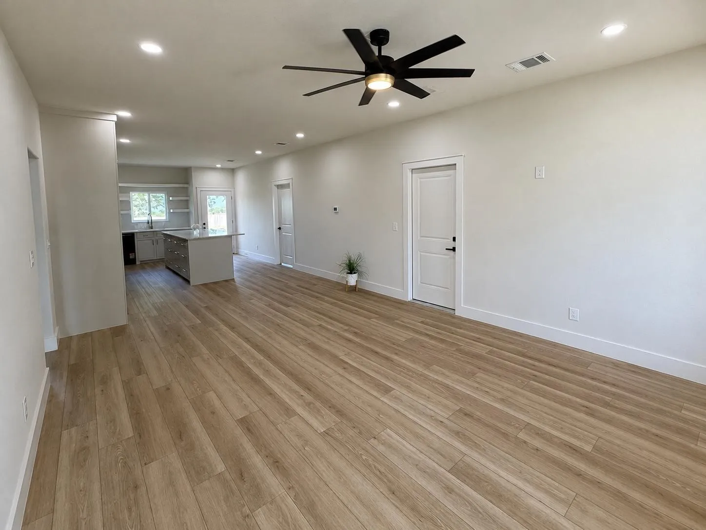 Spacious open-concept living area featuring wood-finish flooring, recessed lighting, and a modern ceiling fan