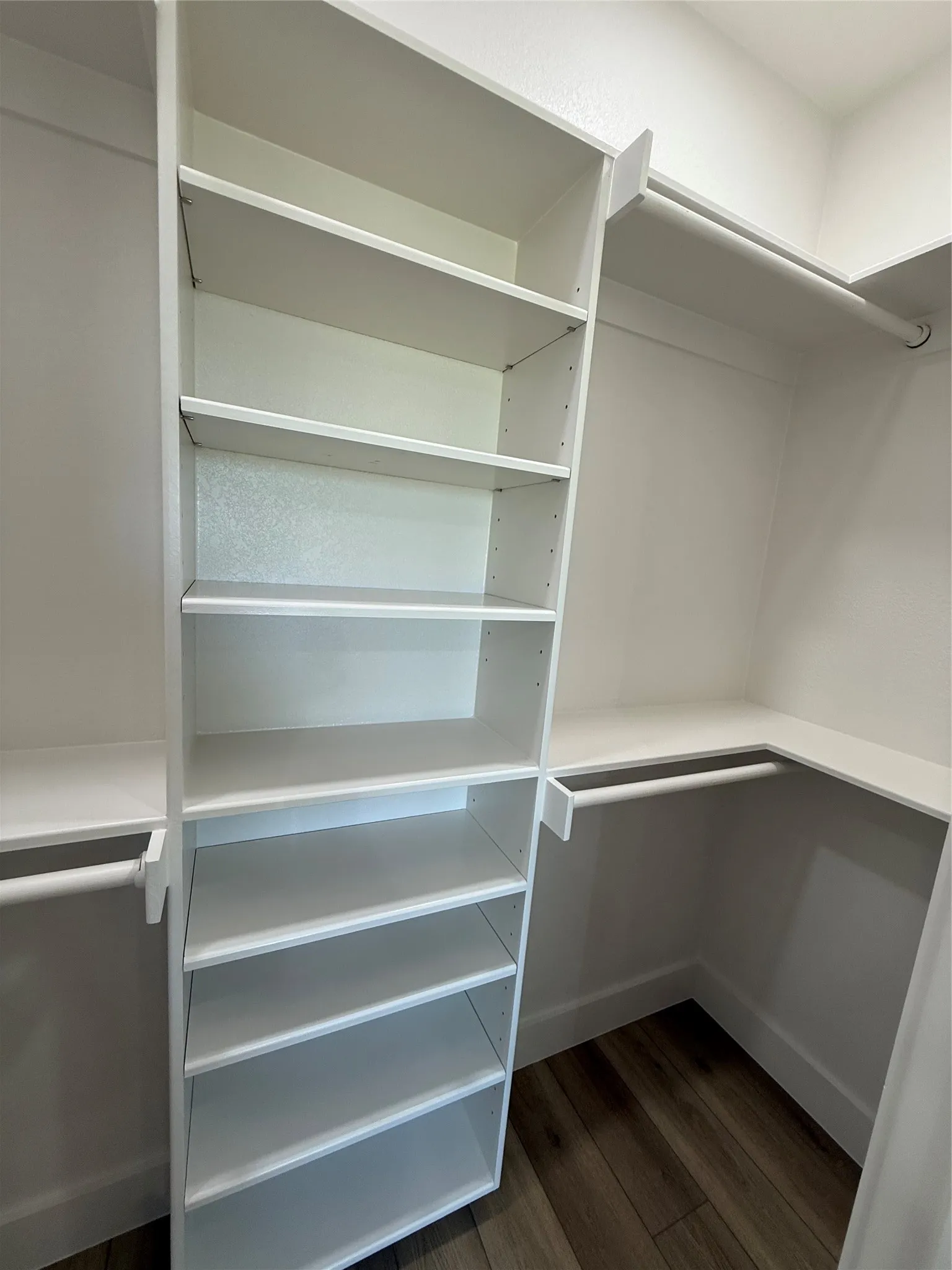 Built-in closet system featuring multiple white shelving units and hanging rods