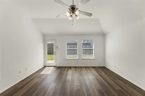 Spacious room featuring wood-finish flooring, vaulted ceiling, and a ceiling fan with integrated lighting