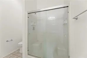 Enclosed shower with clear glass sliding doors and white tile surround
