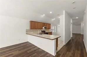 Kitchen and dining area featuring wood-finish flooring, light wood cabinetry, a breakfast bar, and recessed lighting
