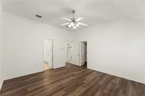 Spacious room featuring vaulted ceilings, a ceiling fan with integrated lighting, wood-finish flooring, and white painted walls