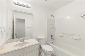 Bathroom featuring a vanity with an integrated sink, a large wall-mounted mirror, and a chrome light fixture