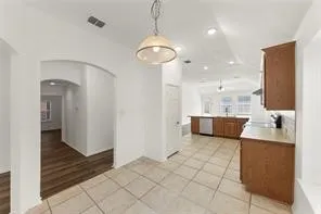 Kitchen area featuring tile flooring, wooden cabinetry, light-colored countertops, stainless steel appliances, and recessed lighting