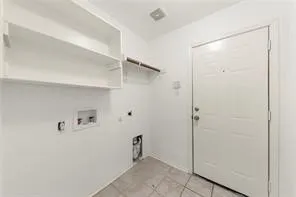 Laundry area with white tile flooring, built-in shelving, and a hanging rod