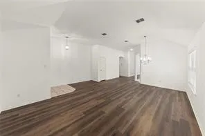 Spacious interior featuring wood-finish flooring, vaulted ceilings, white walls, a chandelier, and recessed lighting