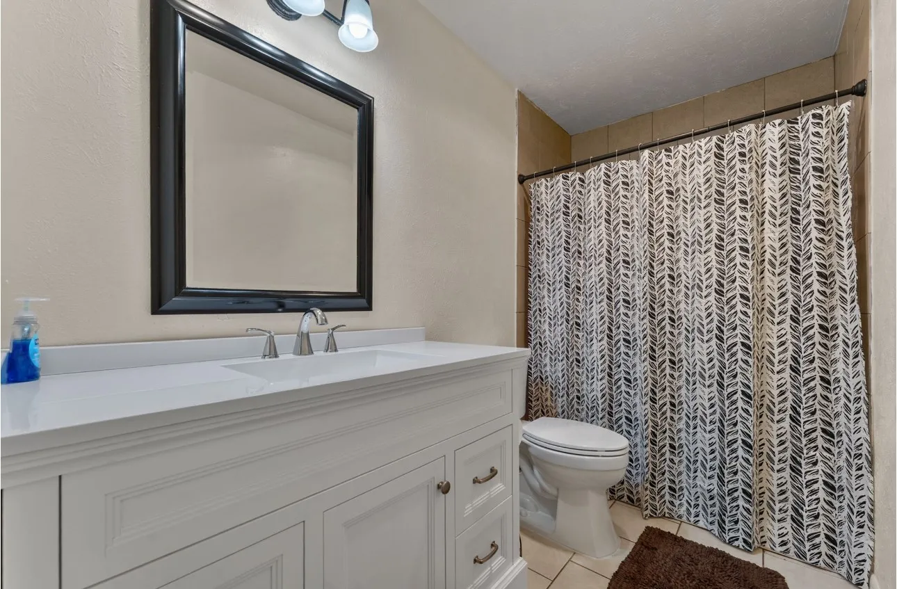 White vanity with an integrated sink, brushed nickel faucet, and framed mirror