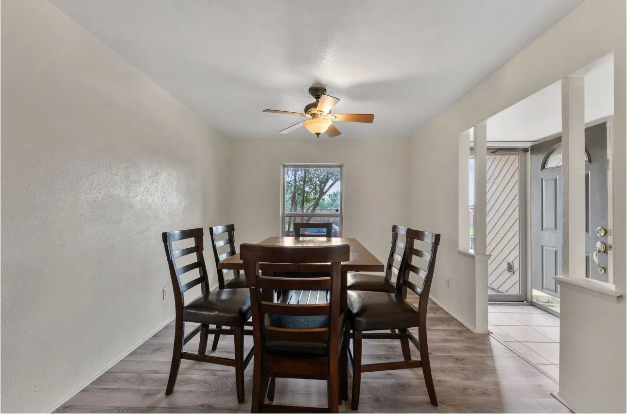 Wood-finish flooring throughout, ceiling fan with integrated lighting, and a window providing natural illumination