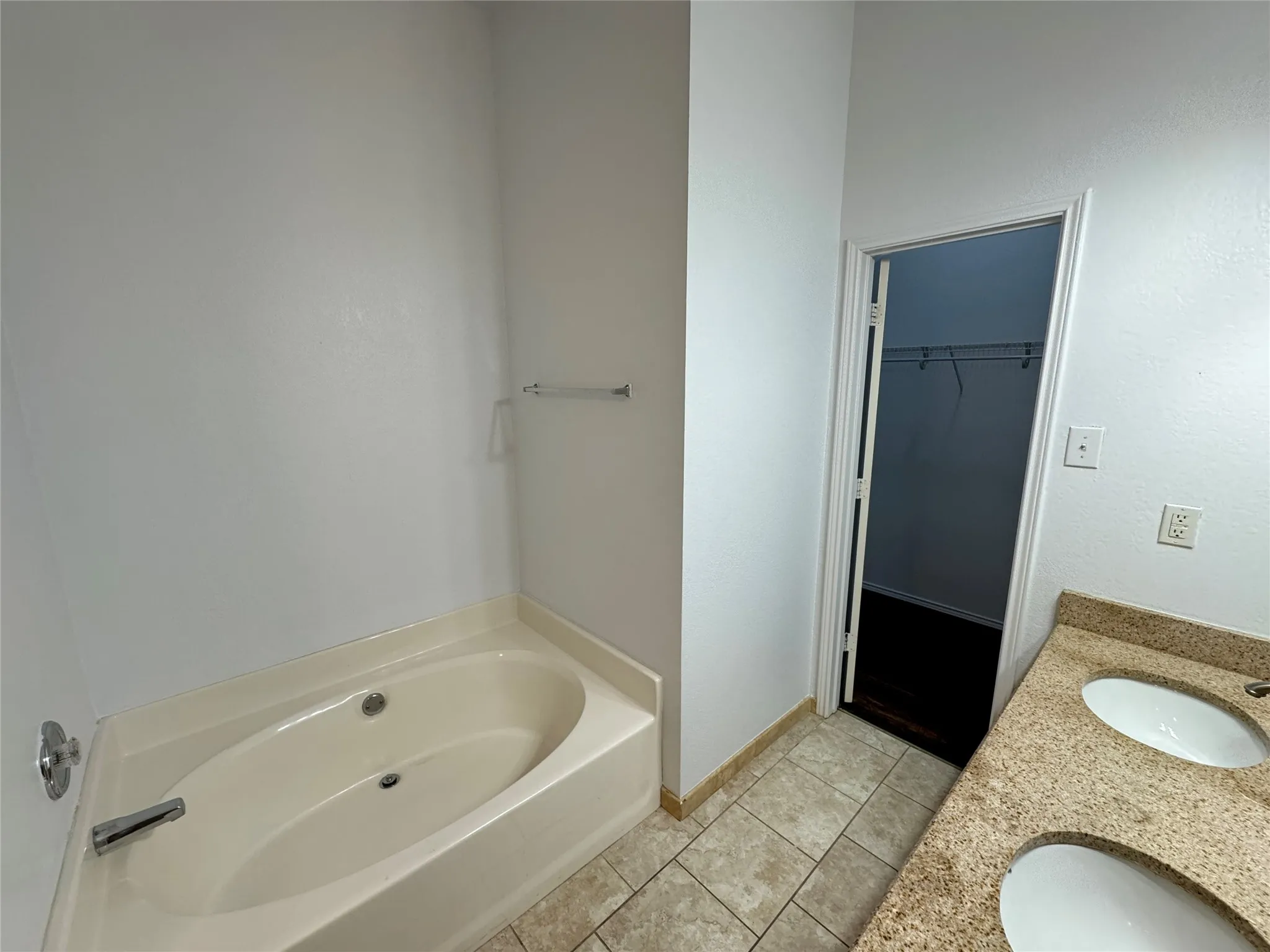 Bathroom with a bath, double vanity, and tile floors