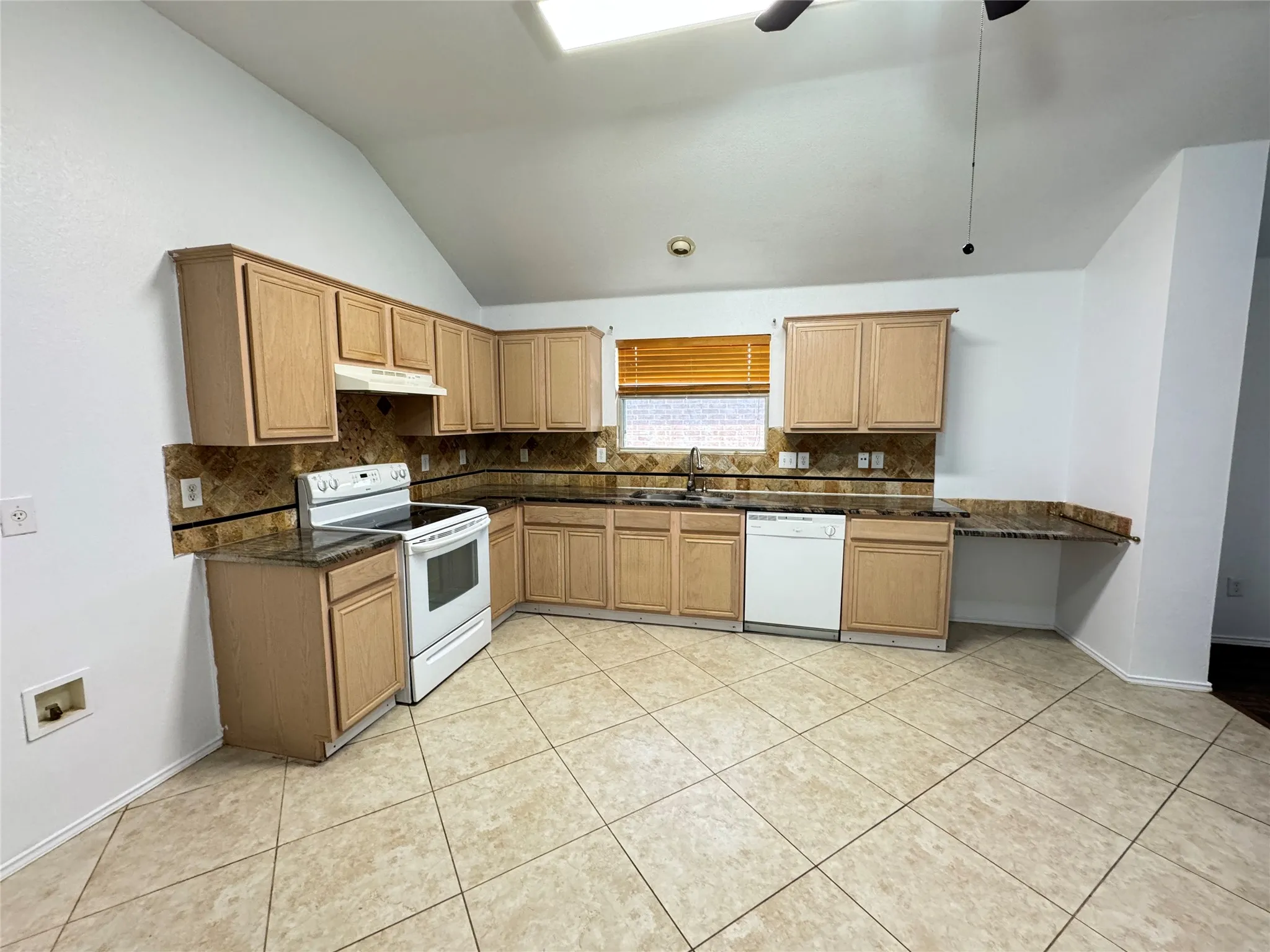 Kitchen with dark stone counters, ceiling fan, tasteful backsplash, white appliances, and light tile floors