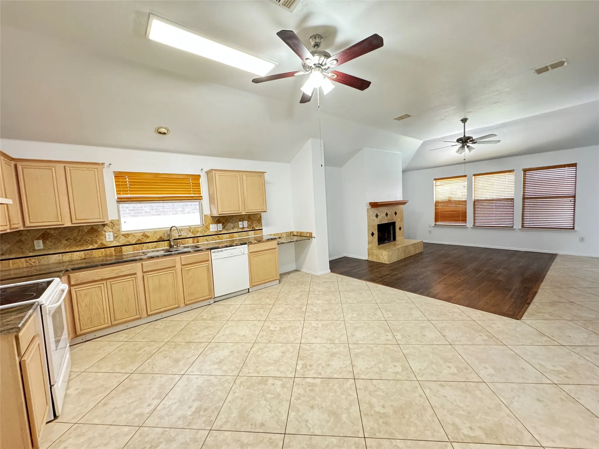Kitchen featuring white appliances, backsplash, ceiling fan, and light hardwood / wood-style flooring