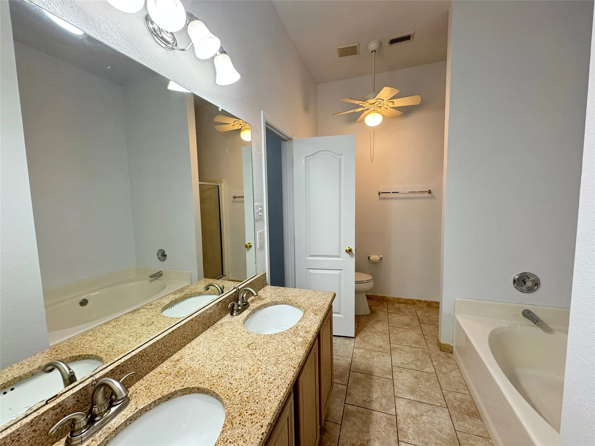 Bathroom featuring a bath to relax in, tile floors, dual bowl vanity, ceiling fan, and toilet