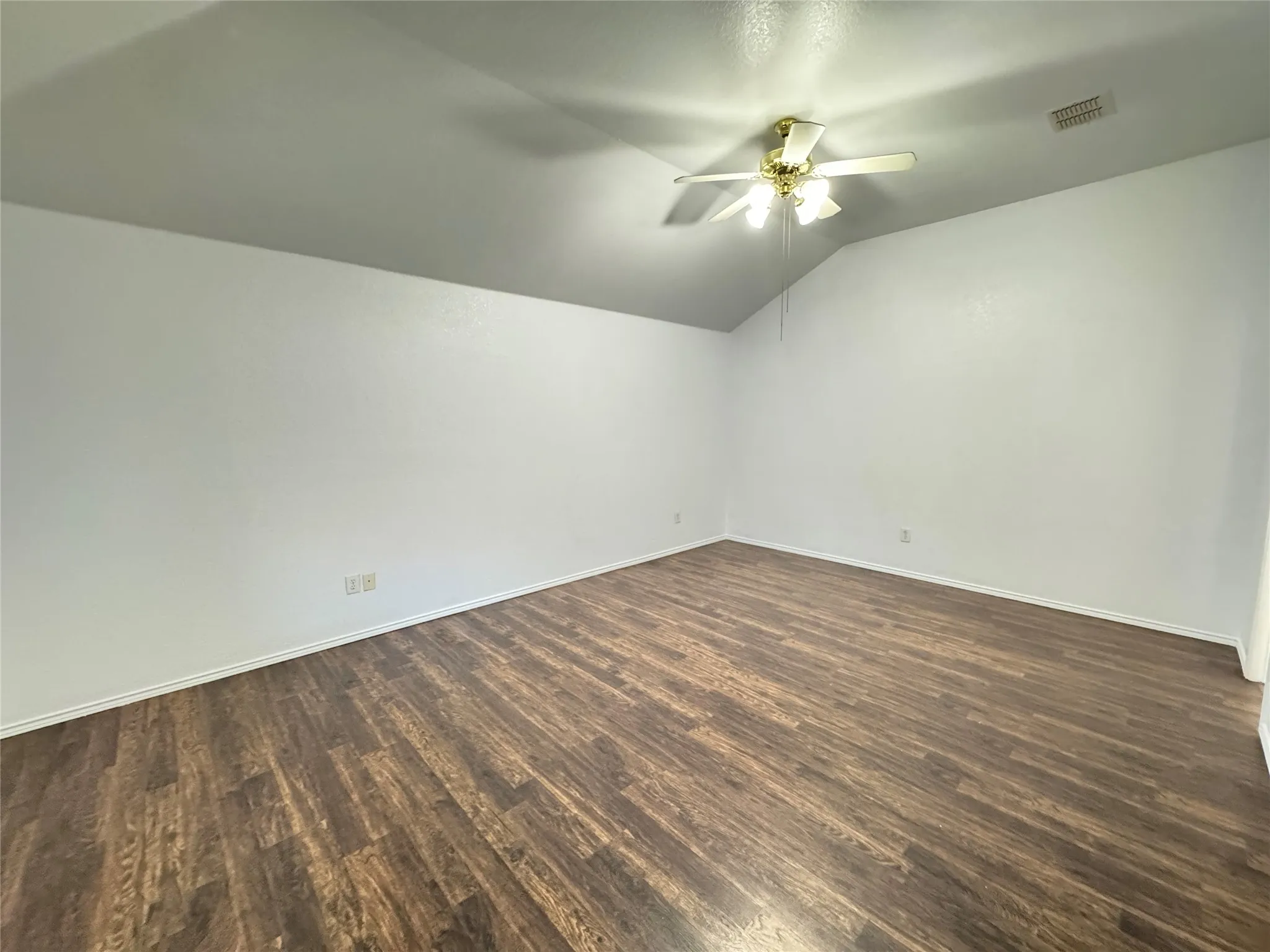 Empty room with dark hardwood / wood-style floors, ceiling fan, and lofted ceiling