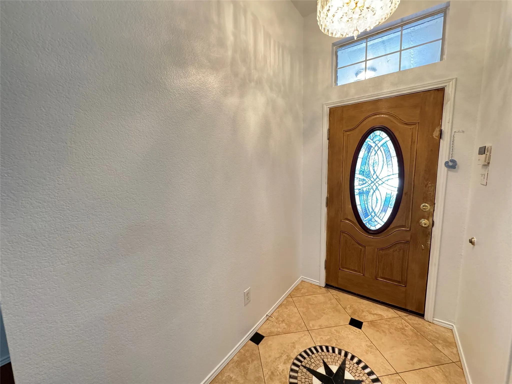Foyer entrance with a chandelier and light tile floors