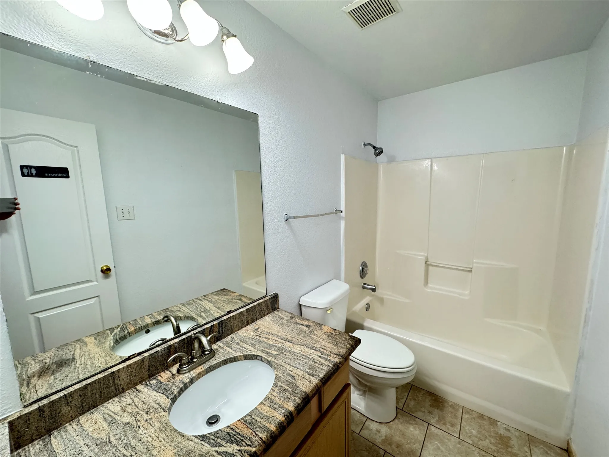 Full bathroom featuring washtub / shower combination, vanity, toilet, and tile floors