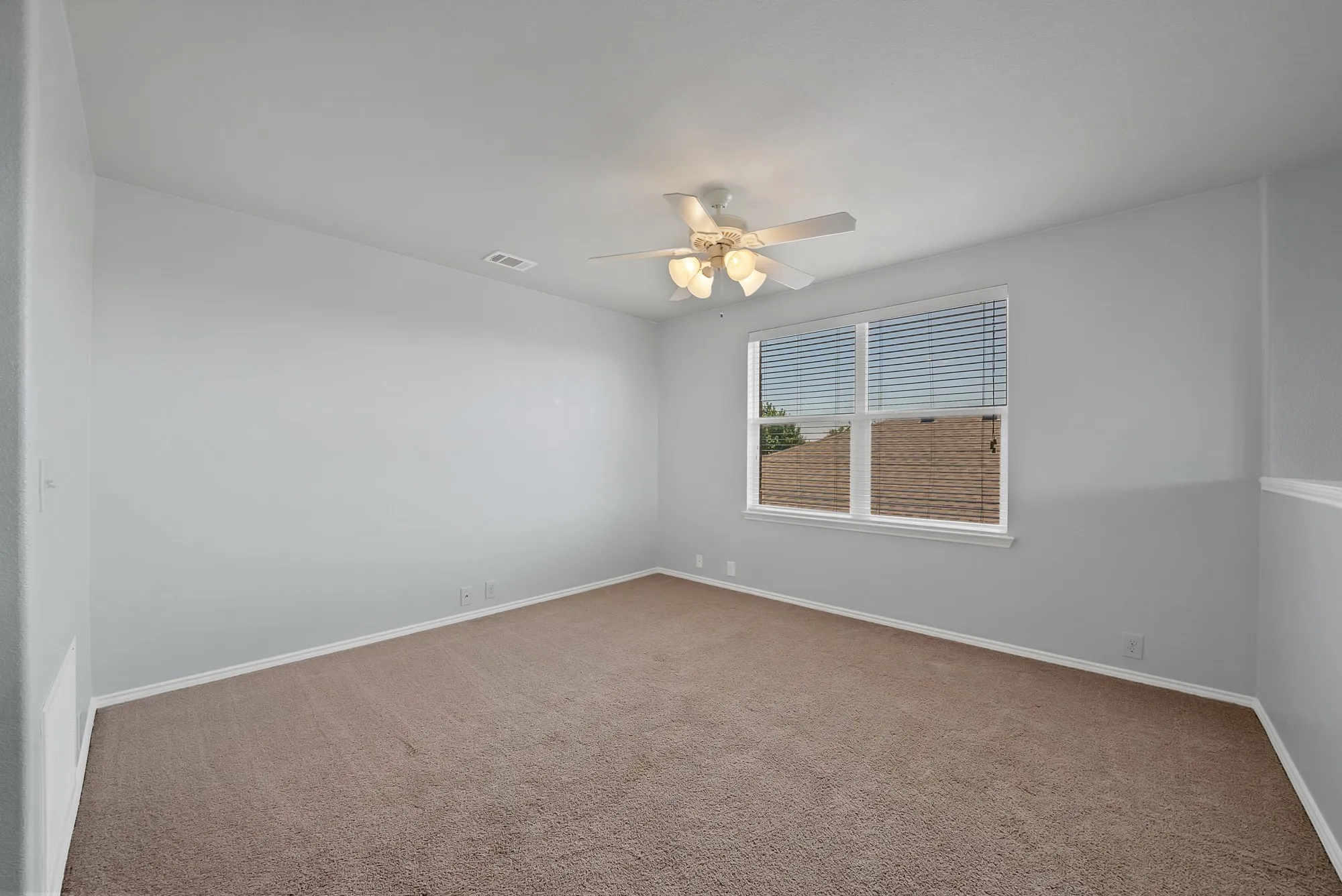 Carpeted room with a ceiling fan, baseboard molding, and a double window with blinds