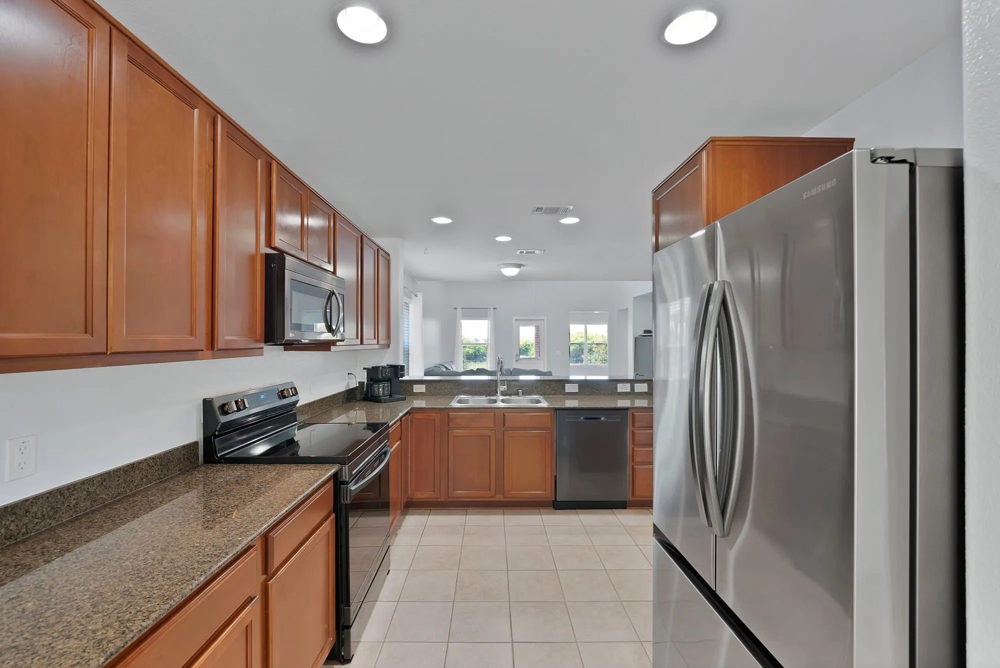 Kitchen featuring wood cabinetry, granite-style countertops, stainless steel appliances, and recessed lighting