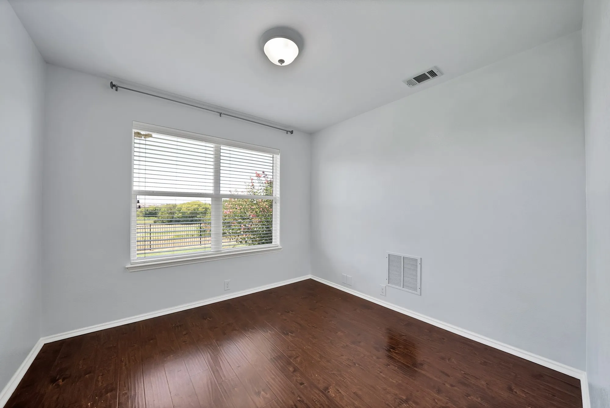 Room featuring wood-finish flooring, light grey walls, and white baseboards